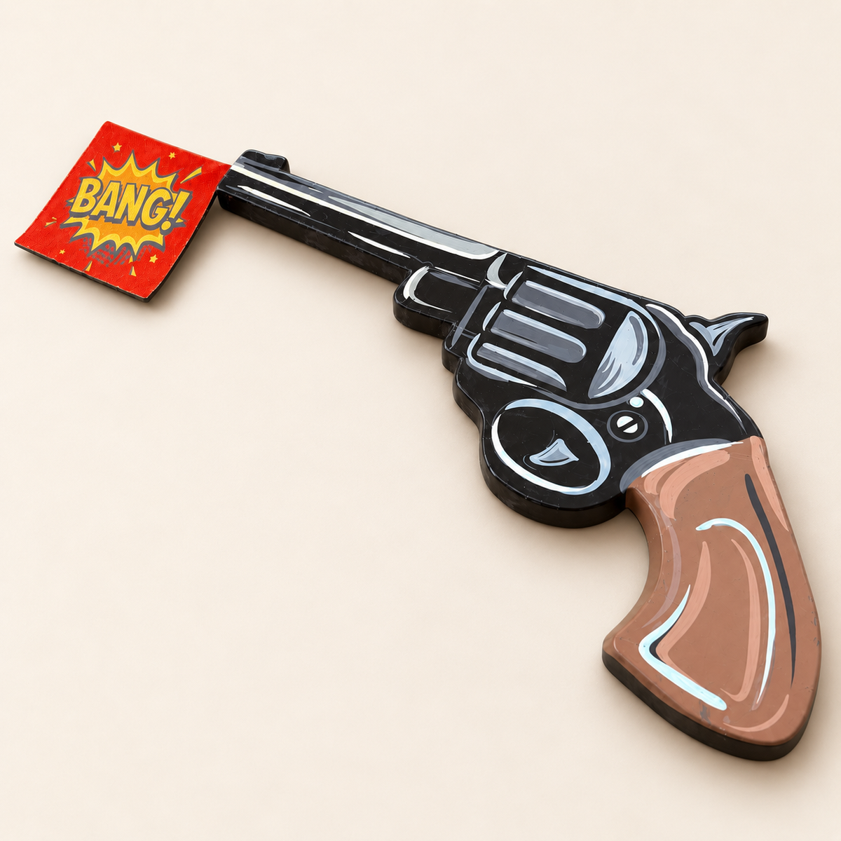 BANG! revolver wall art viewed from the brown painted grip, with a black barrel and red comic flag