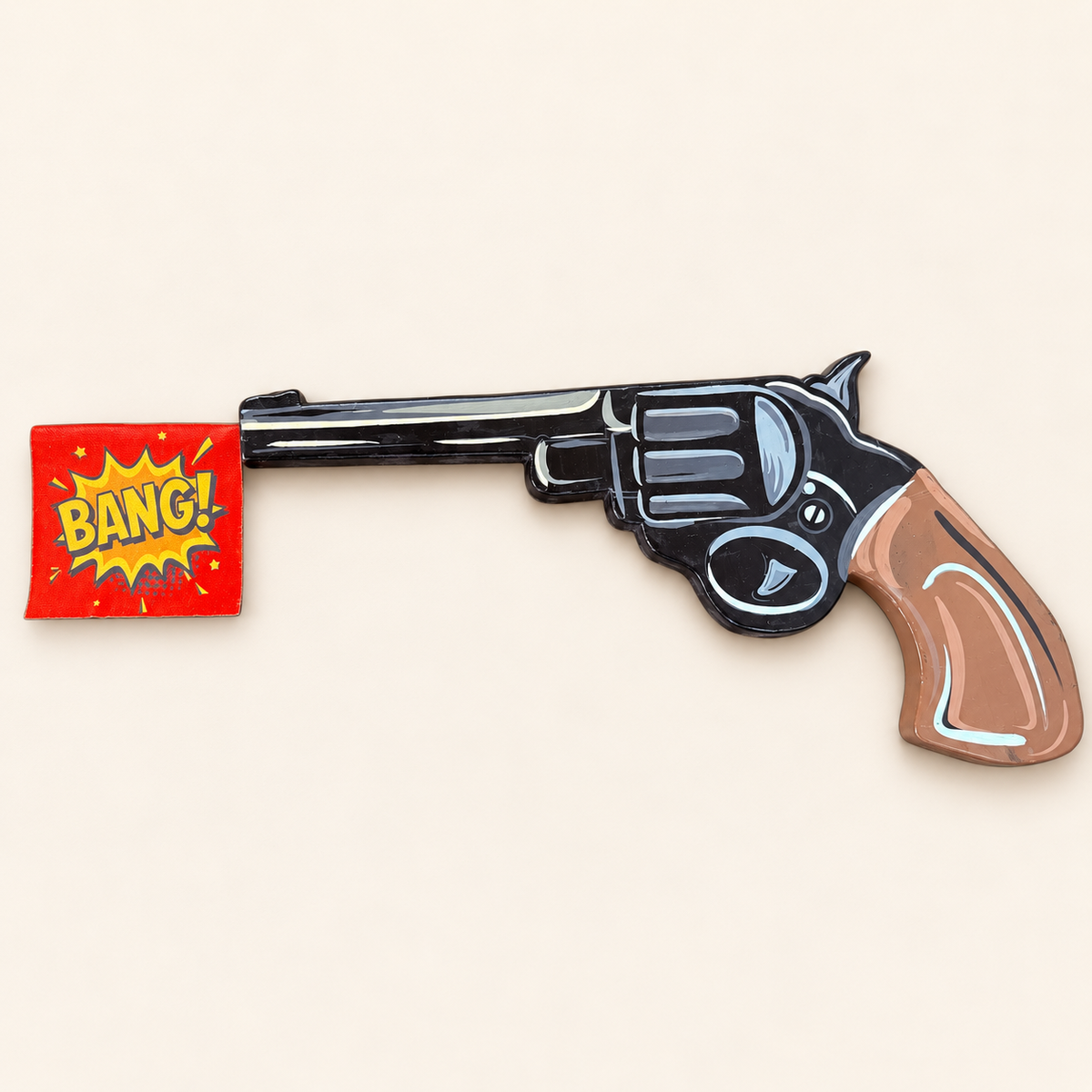 Hand-painted BANG! revolver wall art on MDF, with a brown grip and red comic flag — overhead view