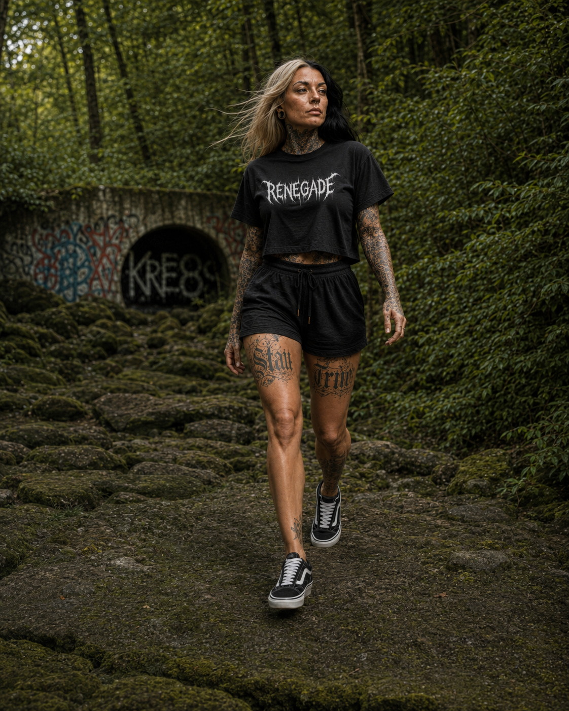 Tattooed model walking on a rocky woodland path in black Vans wearing the Original Renegade Deathcore Crop Tee