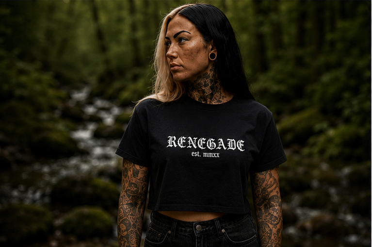 Female model wearing black Renegade Logo Crop Tee with white front print beside a woodland stream