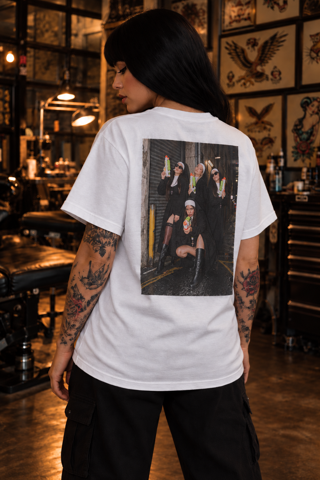 Super Sinner white graphic tee on tattooed female model, rear three-quarter view